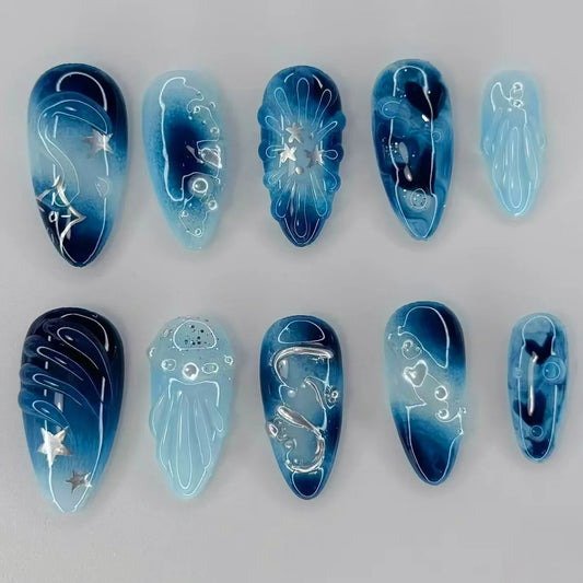 Mid-length almond press on fake nails in a blue smudge design with 3D ripple heart, pearl, and star decorations.