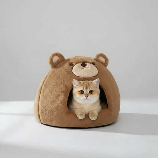 A brown plush bear-shaped cat bed with a cat sitting inside, photographed in a bright indoor setting on a white rug.