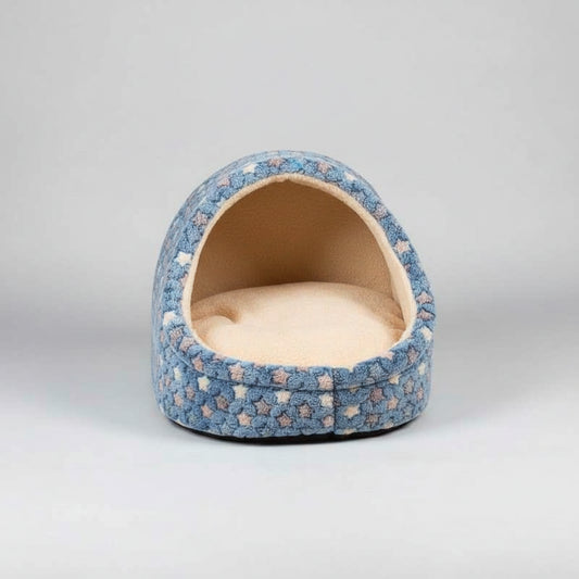 Floral-patterned pet bed on a wooden floor with a plant in the background