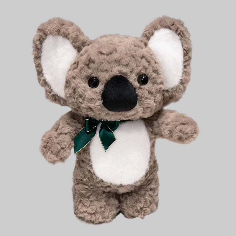 Plush koala toy with a green bow tie on a white surface