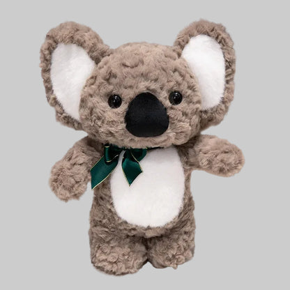 Plush koala toy with a green bow tie on a white surface