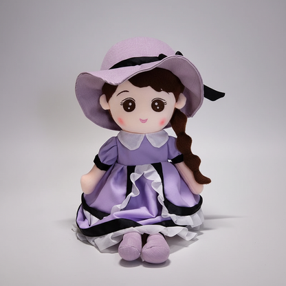 Plush toy with a purple dress and hat on a table with stationery items.