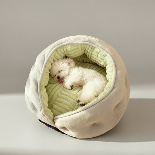 Small white dog lying in a cozy, round pet bed with a soft texture.