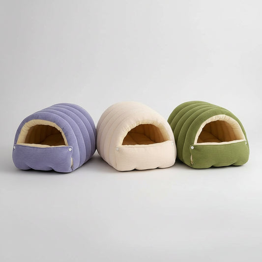 Three pet beds in purple, beige, and green with a small white dog inside one of them.