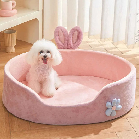 White dog sitting on a pink pet bed with bunny ears in a bright room.